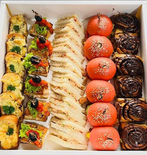 Assorted food items including sandwiches, skewers, and pastries in a box.