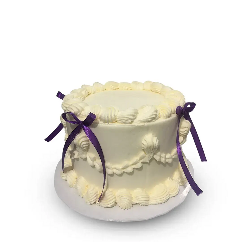 White cake with purple ribbons on a white background